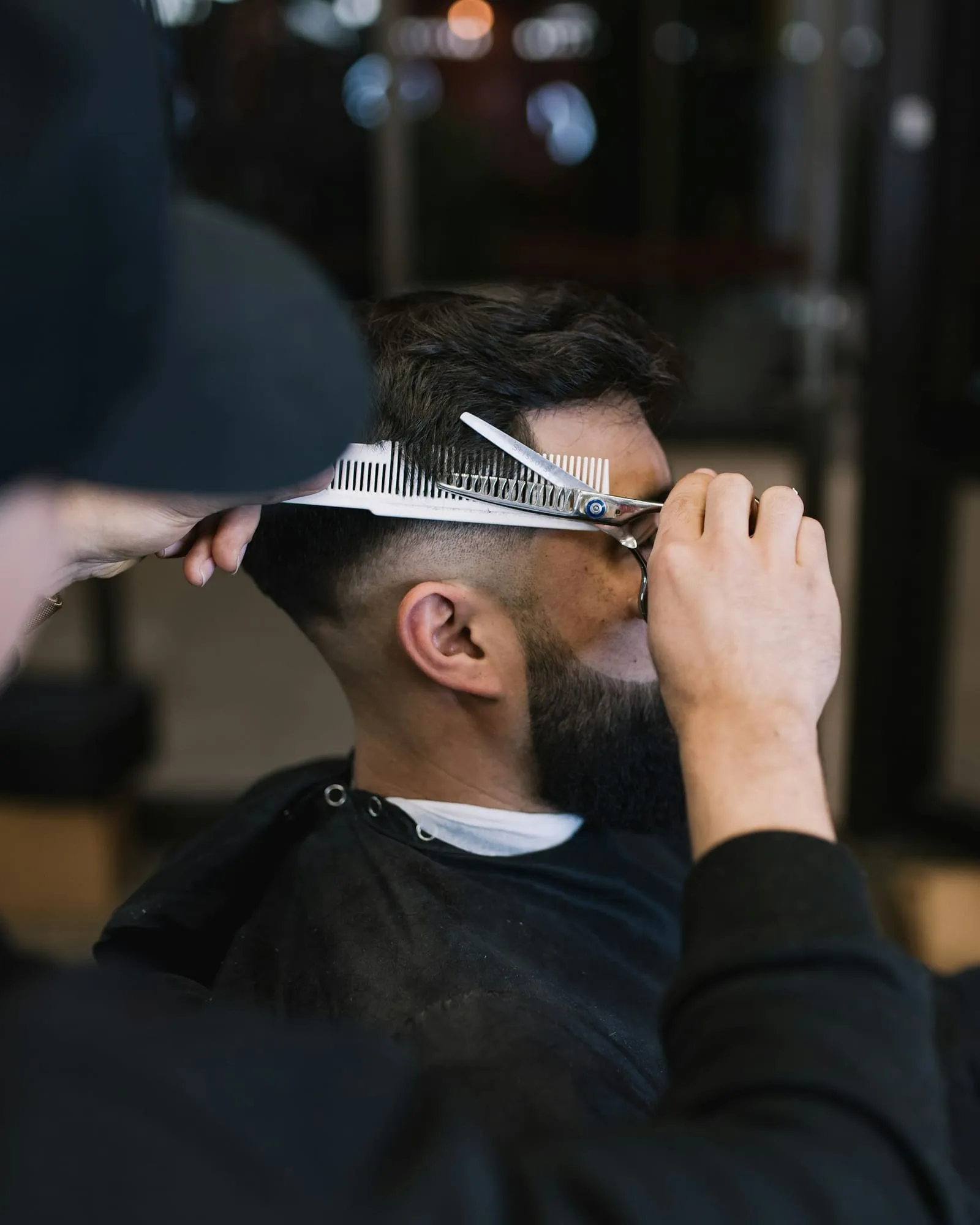 Barbero cortando el pelo a un cliente con tijera y peine